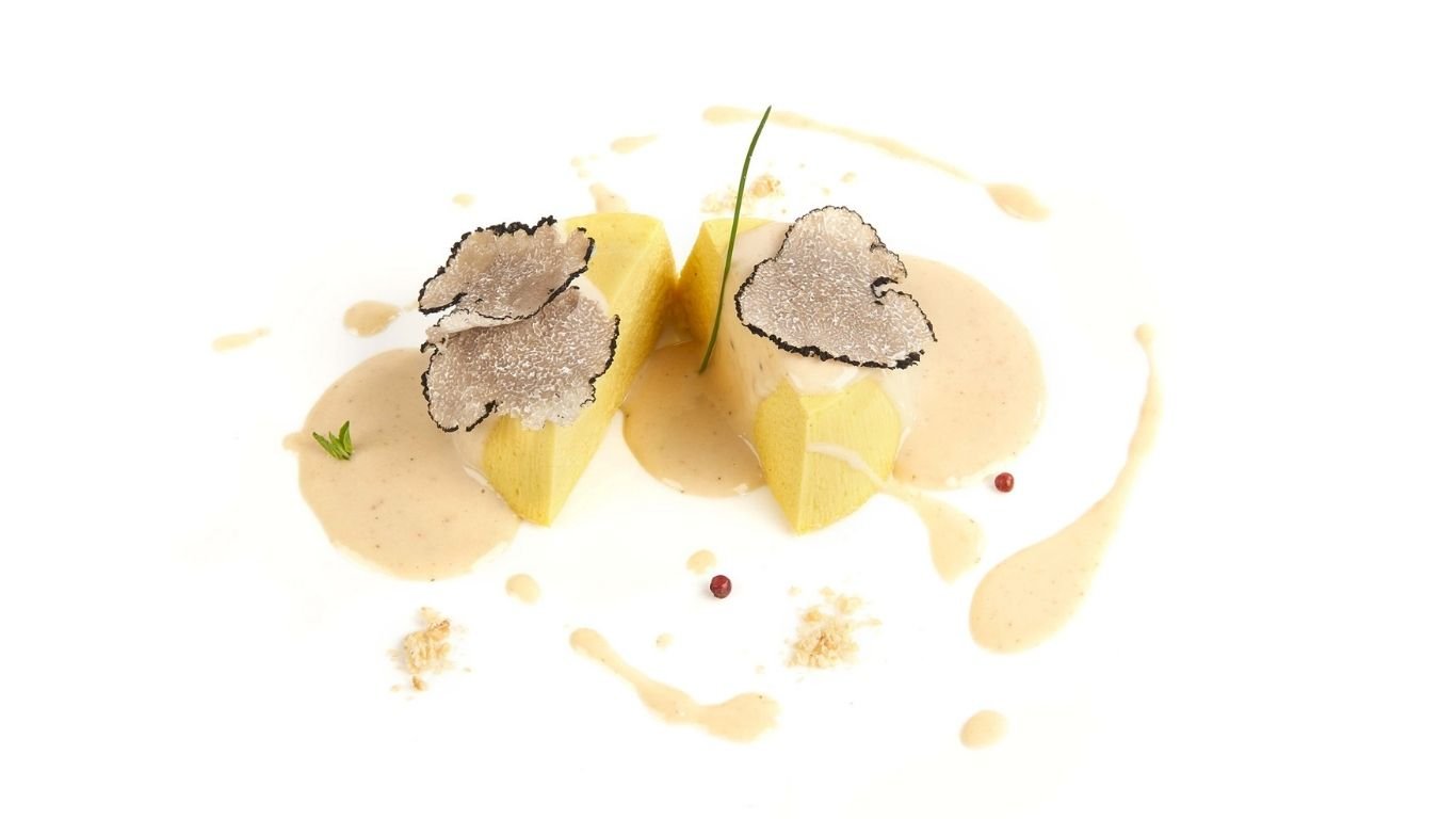 Гурме ястие с кремообразна панакота, гарнирано с нарязан бял трюфел, гарнирано с билки и подчертано с деликатен сос.